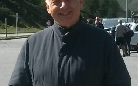 nigel with his hands in his pocket looking at the camera smiling