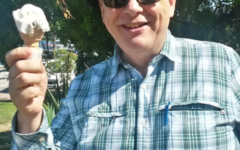 nigel holding an ice cream with sunglasses and a hat on