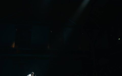 Spotlights on Beibei Wang, leaning over a table with a white tablecloth.
