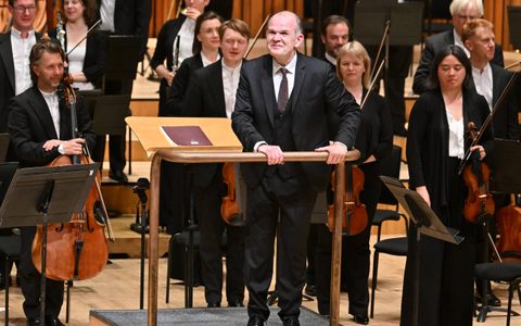 François-Xavier Roth smiles at the audience from the stage