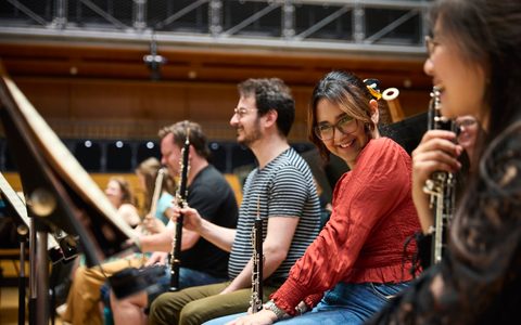Orchestral Artistry student with the Principal Oboe of the LSO during rehearsal, both laughing.