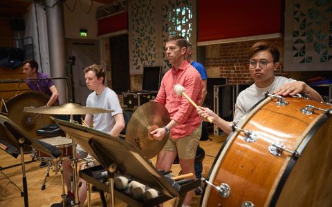 Orchestral Artistry students with an LSO Percussion member during rehearsal, holding different percussion instruments.