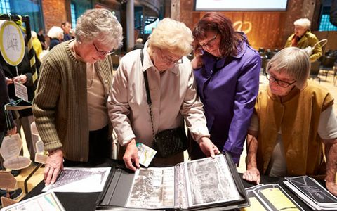 4 women looking at a book of images
