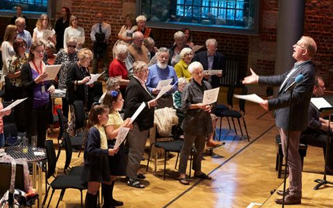 a man singing to group of people with the audience singing along with him