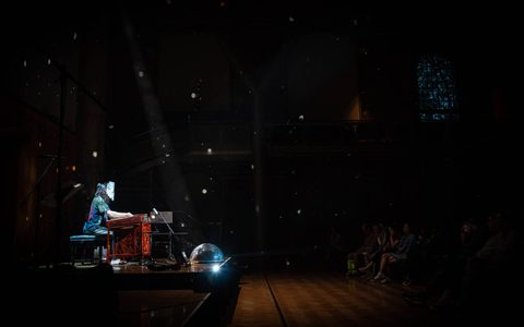 Manta wearing a glittery mask playing the yangqin. There is a disco bowl underneath the instrument.