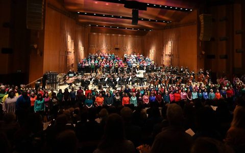 A wide shot of the Barbican stage, with the LSO and London Symphony Chorus on the stage, and LSO Community Voices in front of the stage
