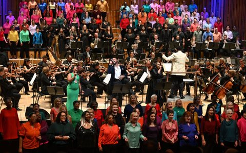 André J Thomas conducting the LSO and choirs on stage, with the LSO Community Voices in front of the stage.