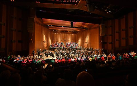 Orchestra and singers in bright clothing on stage