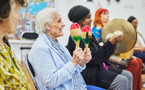 An older woman playing maracas