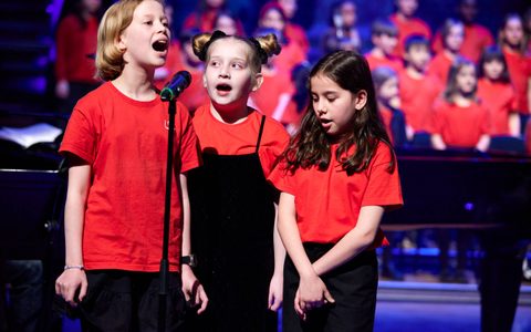 Three young people singing into a shared microphone
