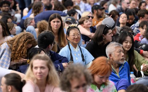 The audience sat watching BMW Classics, focusing on a woman in a blue dress.