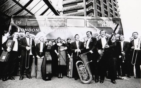 patrick with an orchestra standing in front of a bus